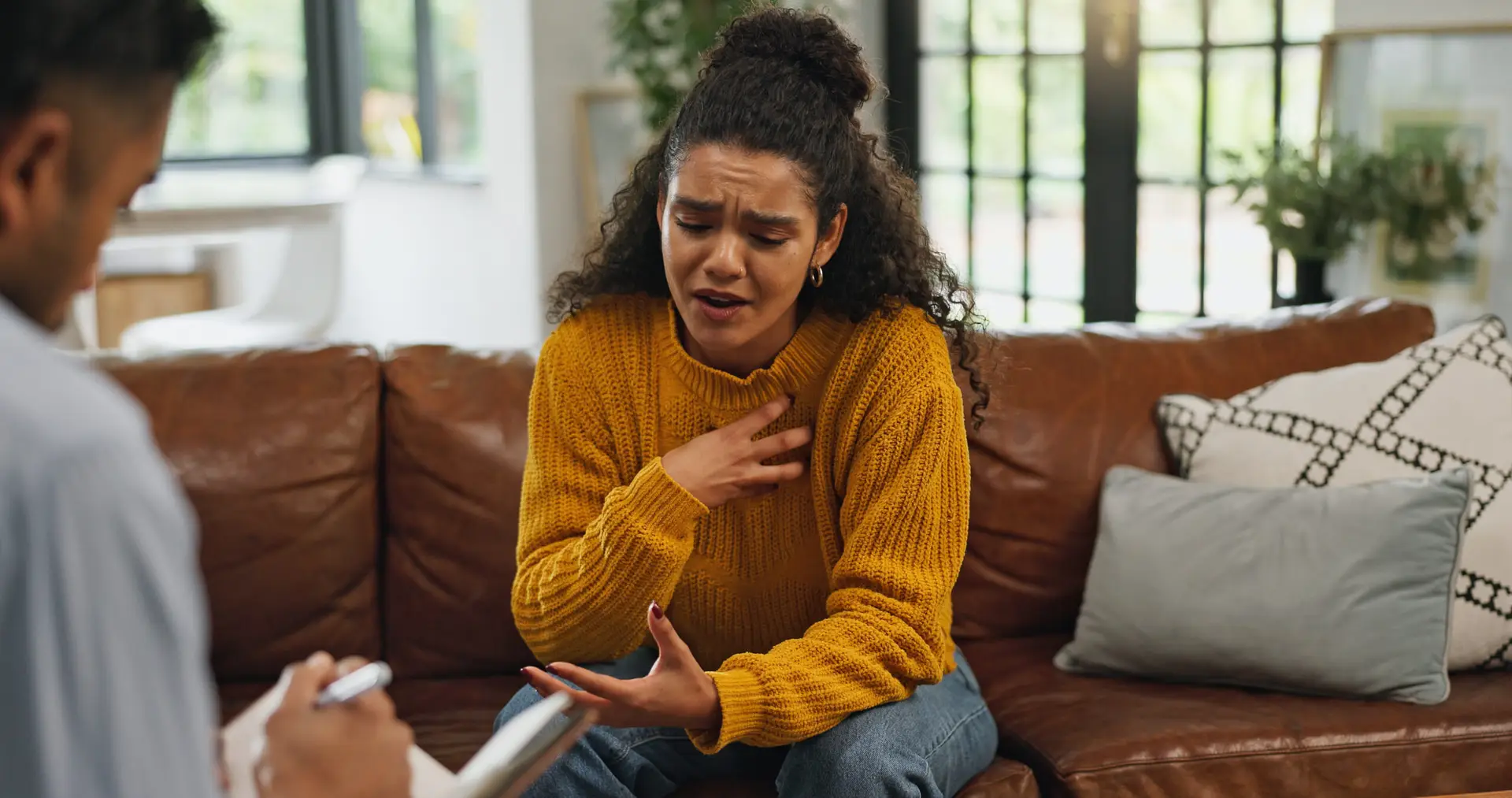 aWoman with high-functioning anxiety sitting on a sofa looking worried